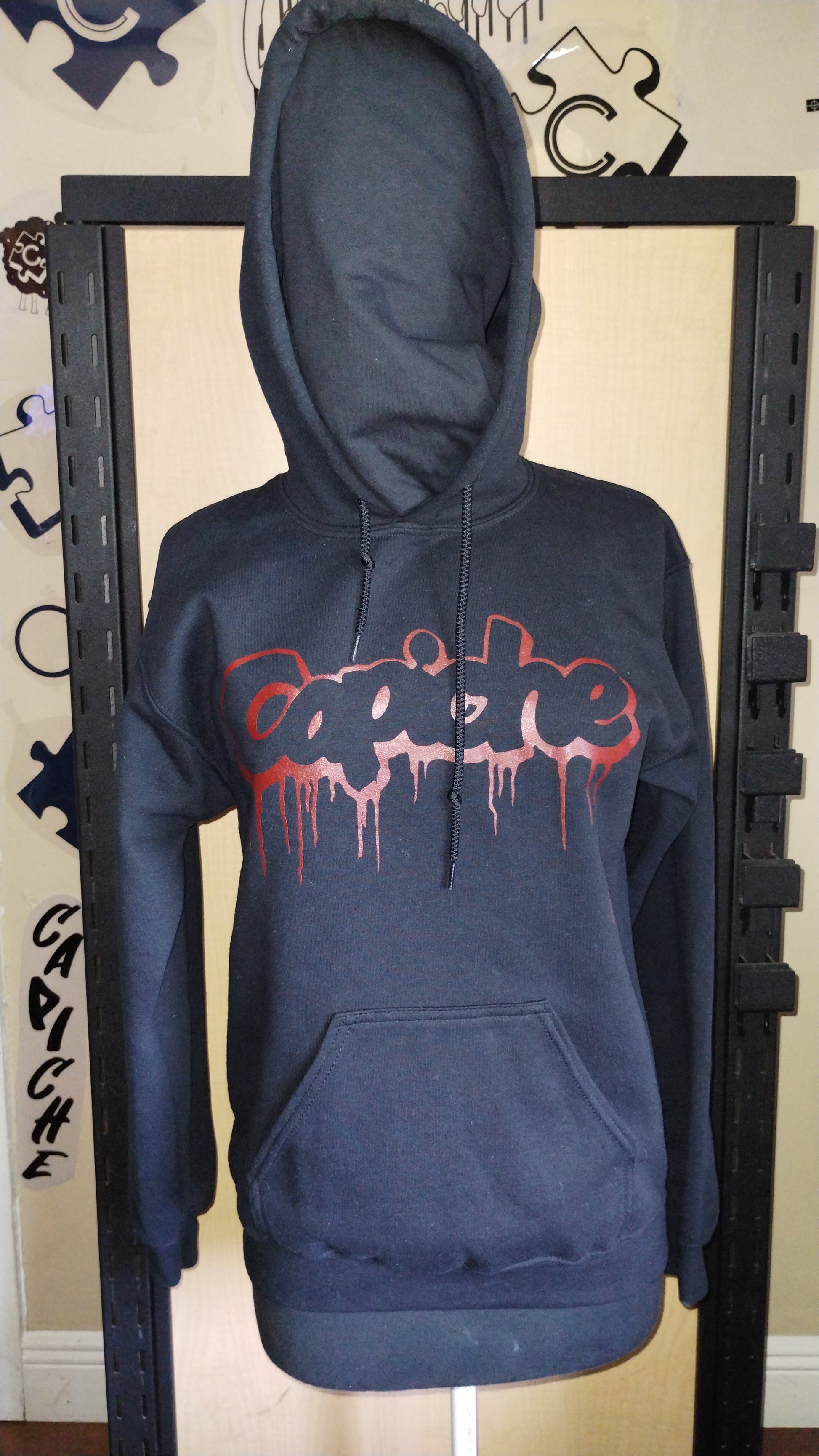 Front view of black hoodie on a manikin. Capiche logo in red ink.