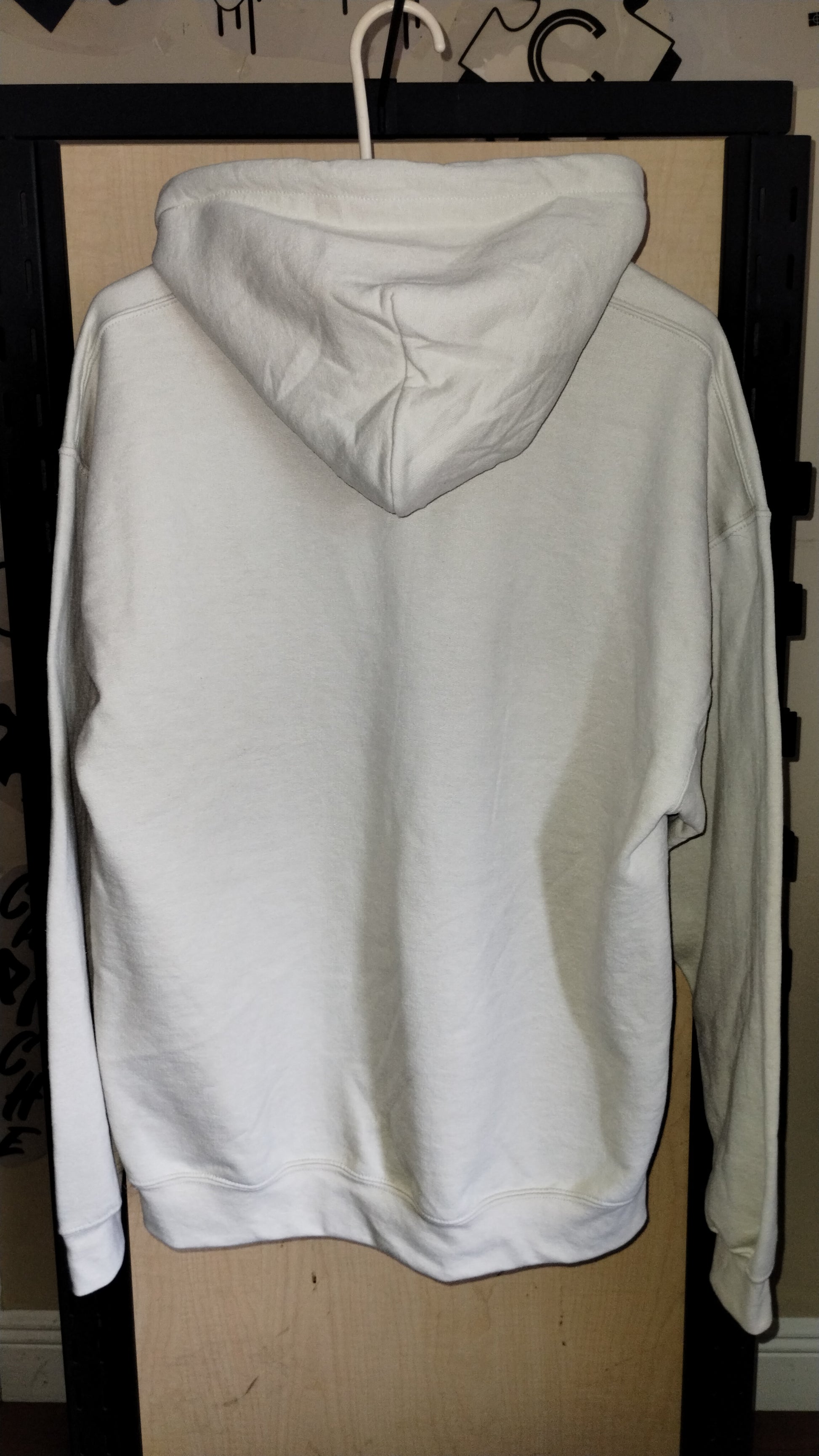 Back view of tan hoodie on a hanger.