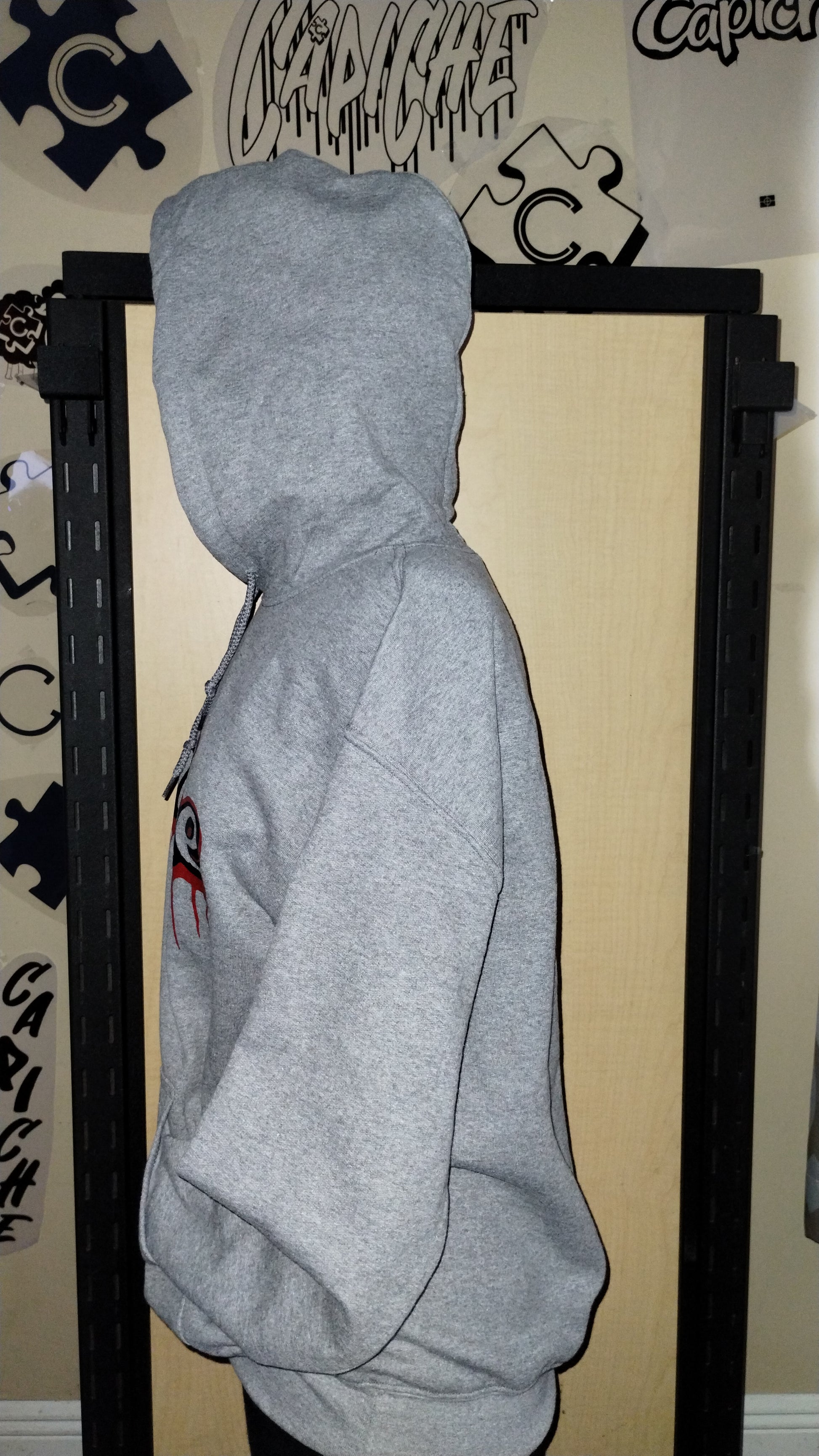 Side view of grey hoodie on a manikin. Capiche logo in black and red ink.