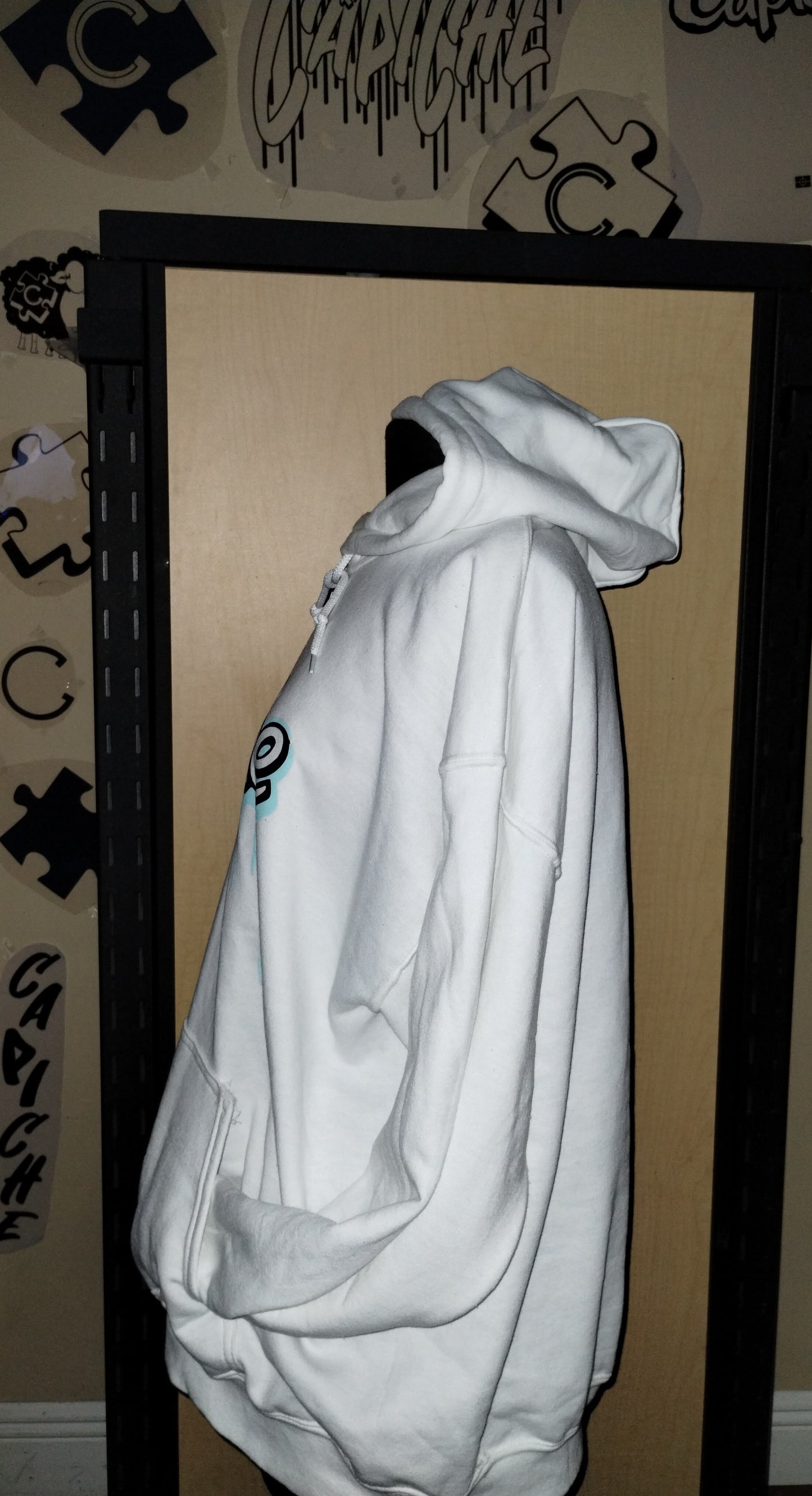 Side view of white hoodie on a manikin. Capiche logo in black and teal ink