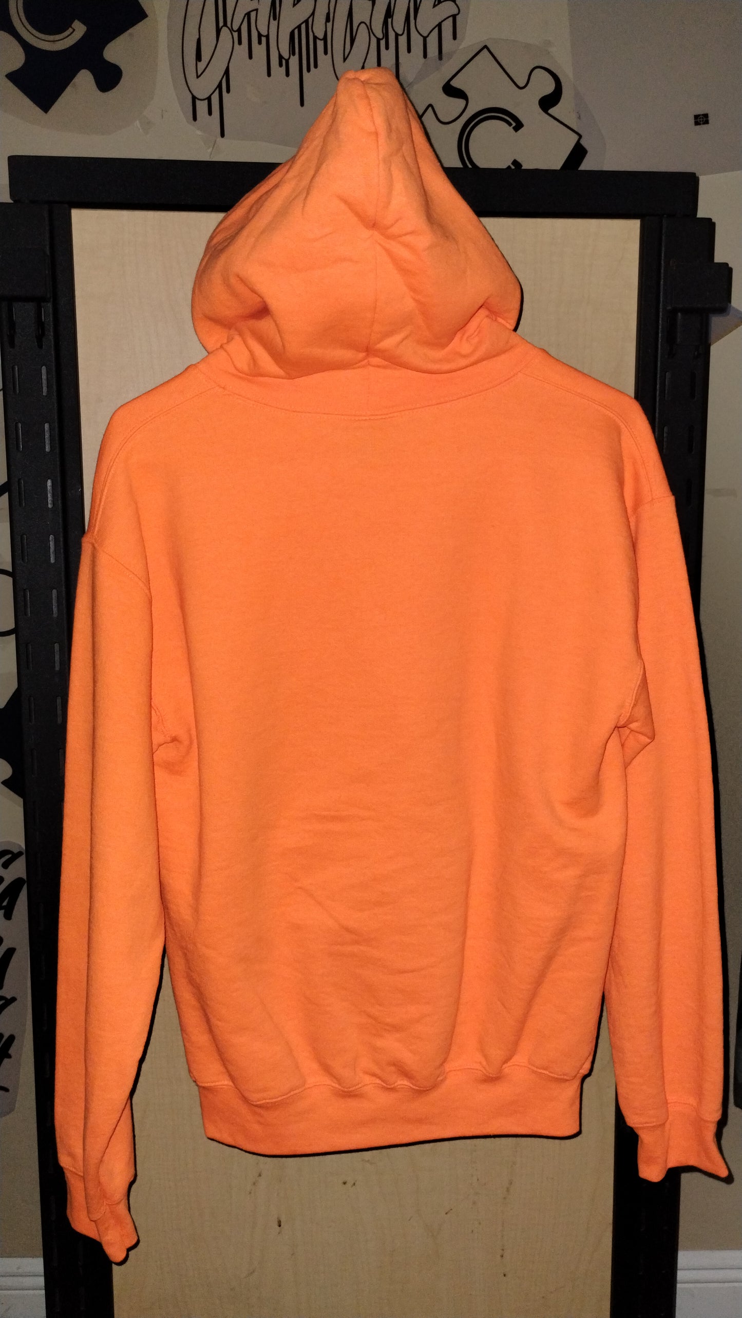 Back of orange hoodie on a hanger.