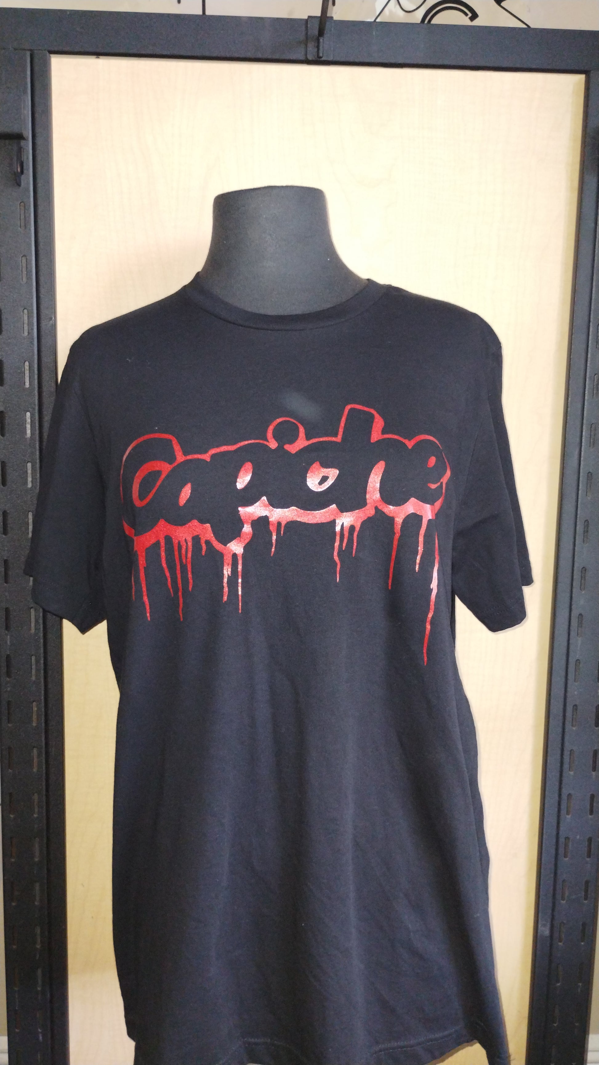 Black shirt on a manikin. Capiche logo on front in red ink.