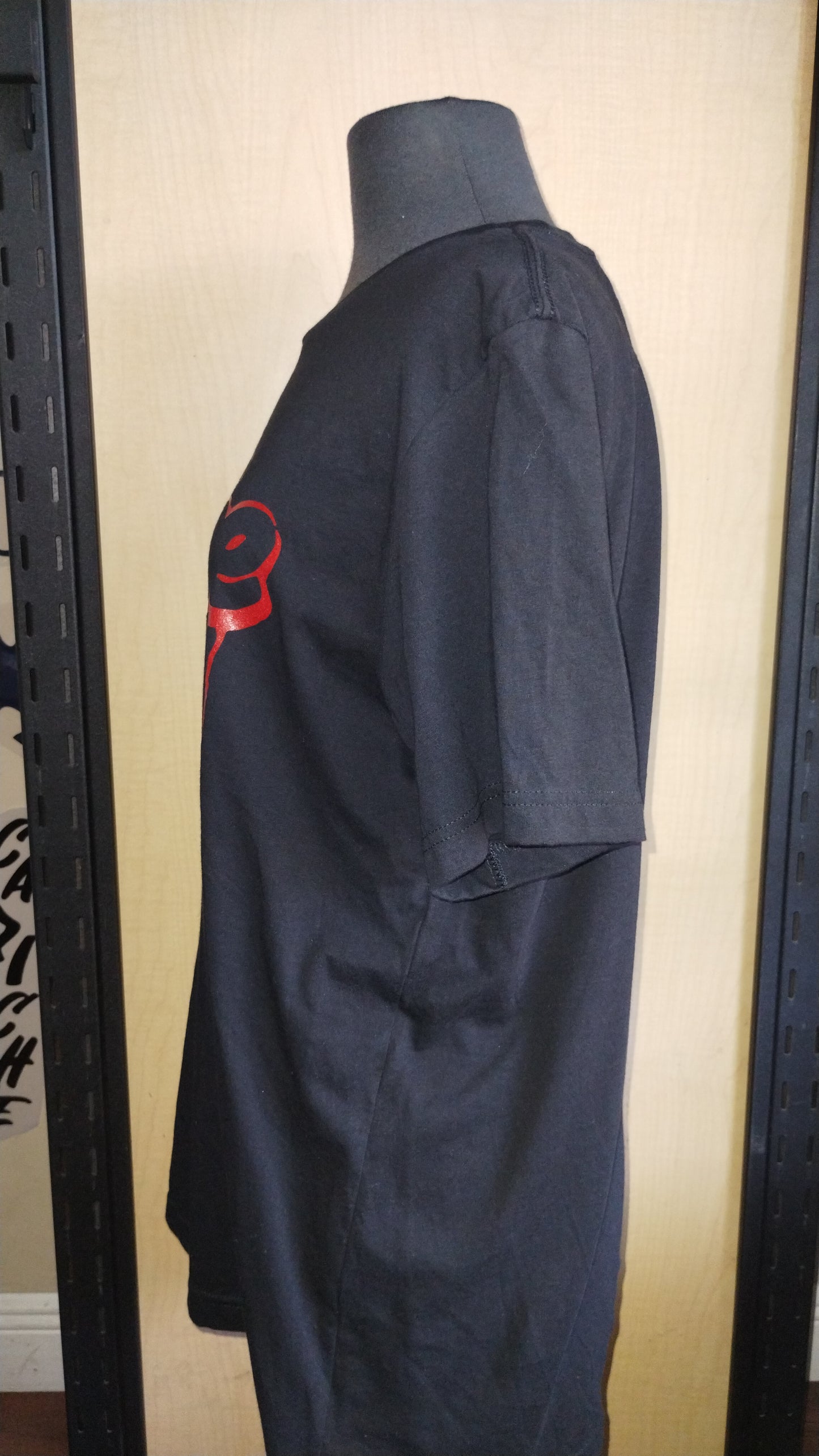 Side view of black shirt on a manikin. Capiche logo in red ink.