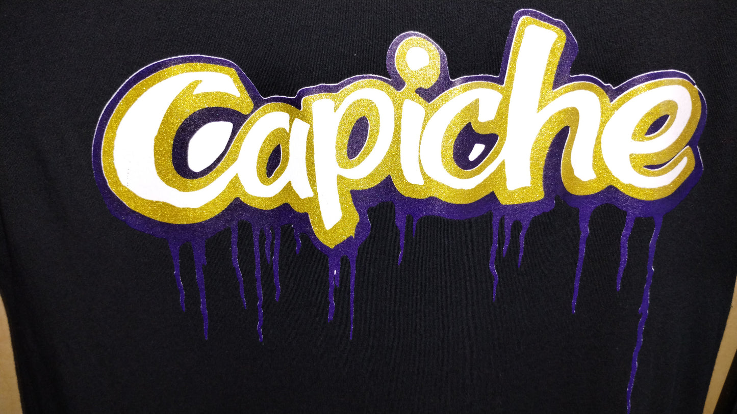 Focused shot of Capiche logo on black shirt. Logo is in white, gold and purple inks.