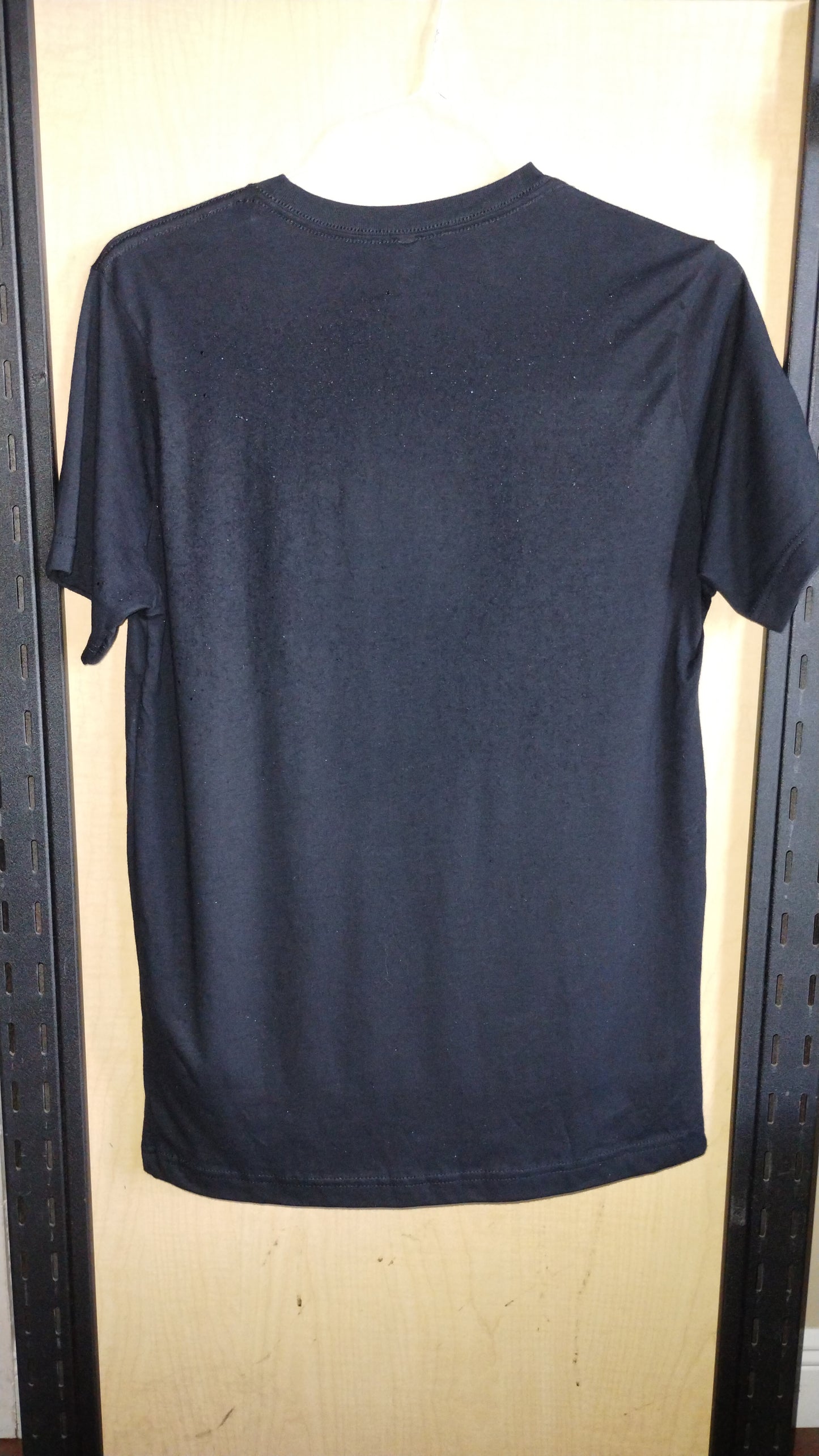 View of back of black shirt on a hanger.