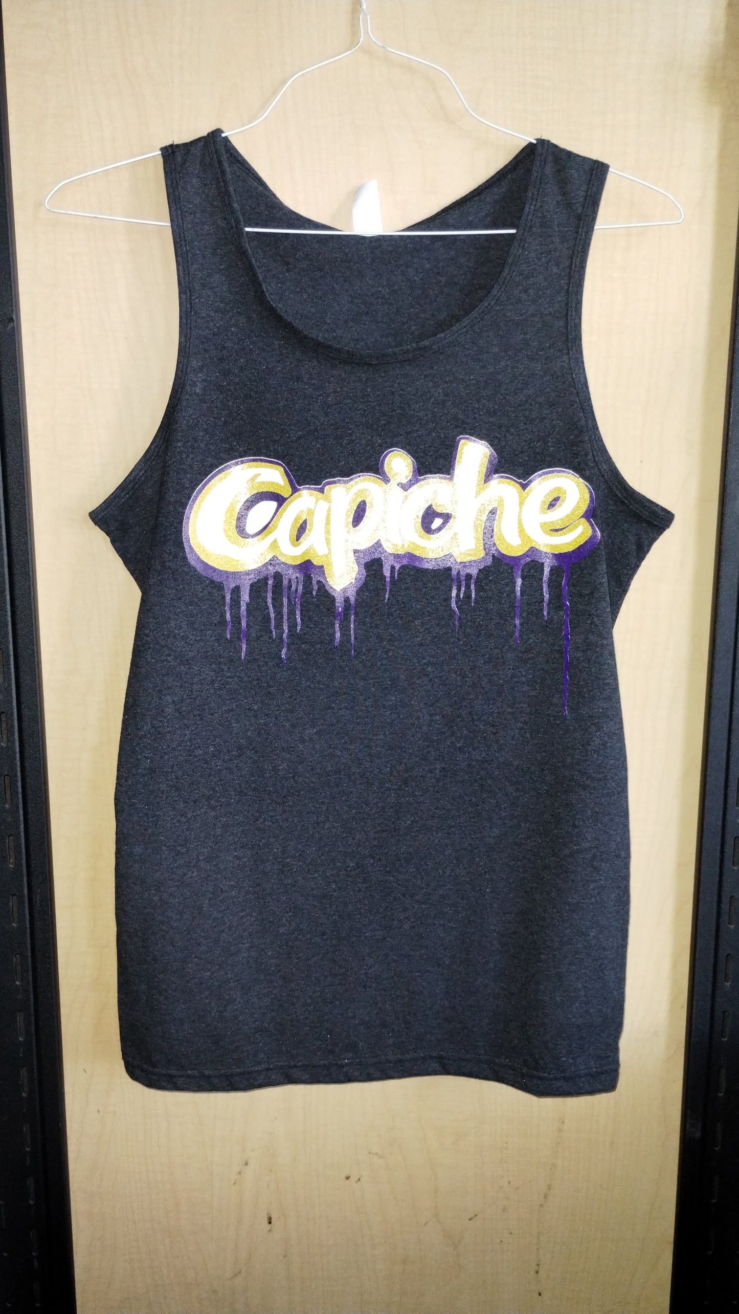 Heathered Grey Unisex Tank top on a hanger. Capiche logo printed on the front in white, gold, and purple inks.