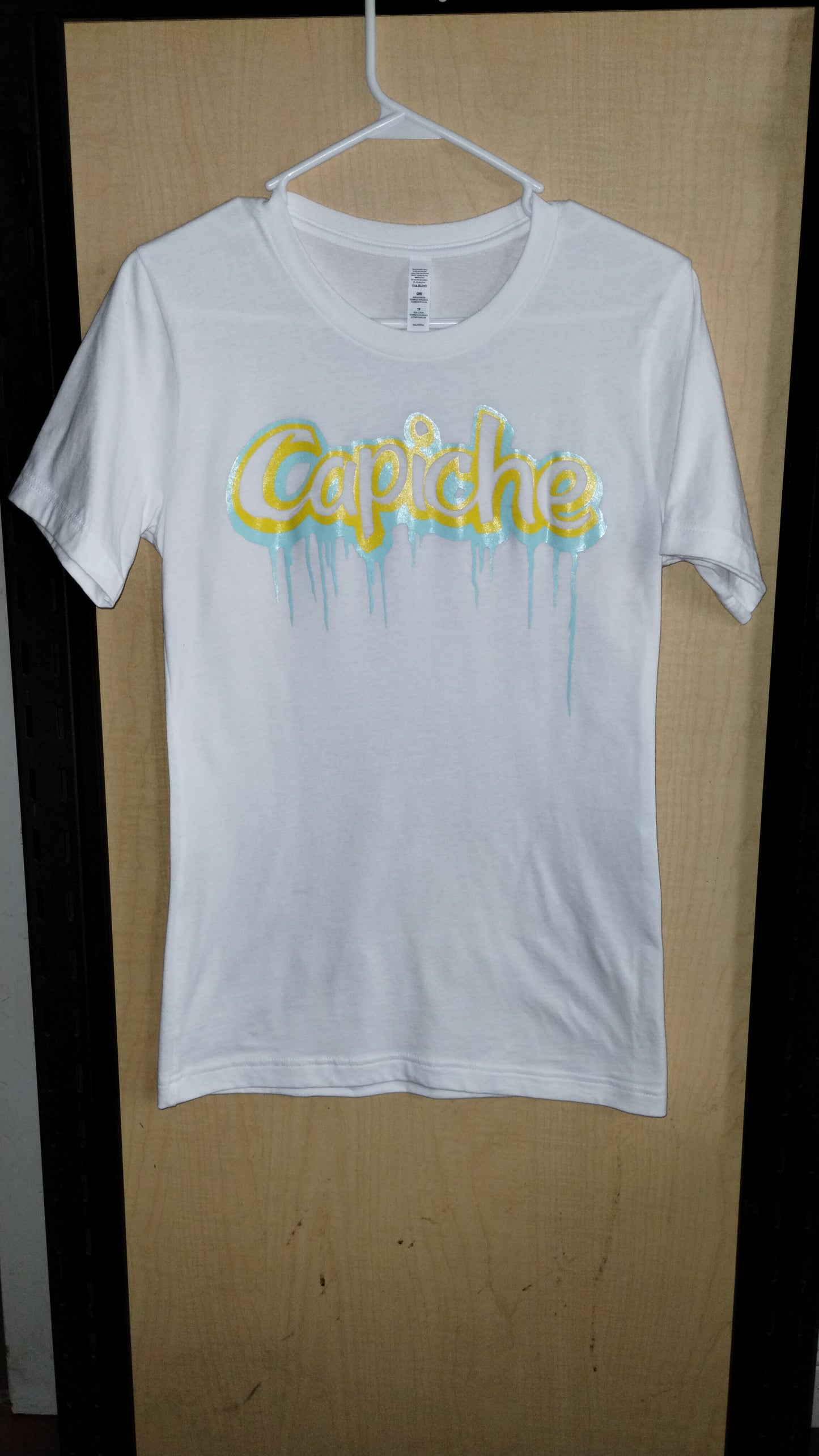 Front view of white shirt on hanger with capiche logo printed on the front in banana yellow and mint.